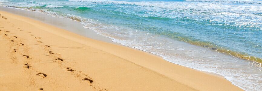 two sets of footprints in the sand on a beach
