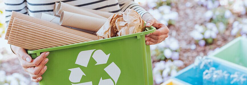 woman holding a recycling bin with recycling materials inside